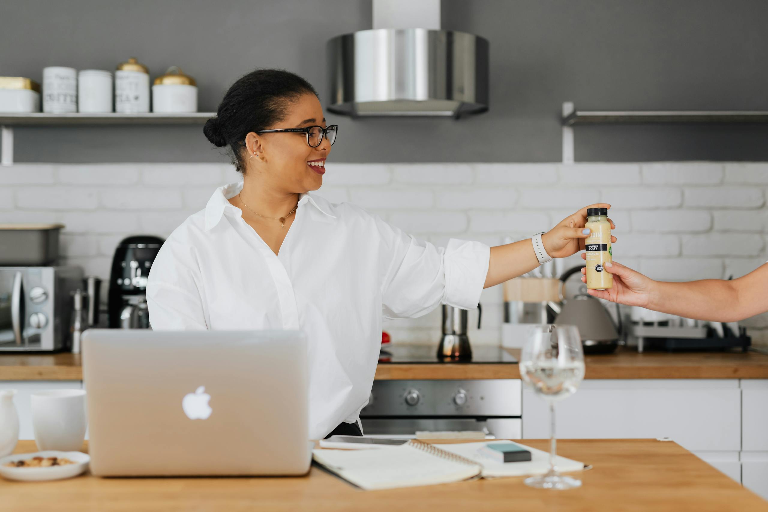 African American woman smiling and holding a drink in a modern kitchen setting.