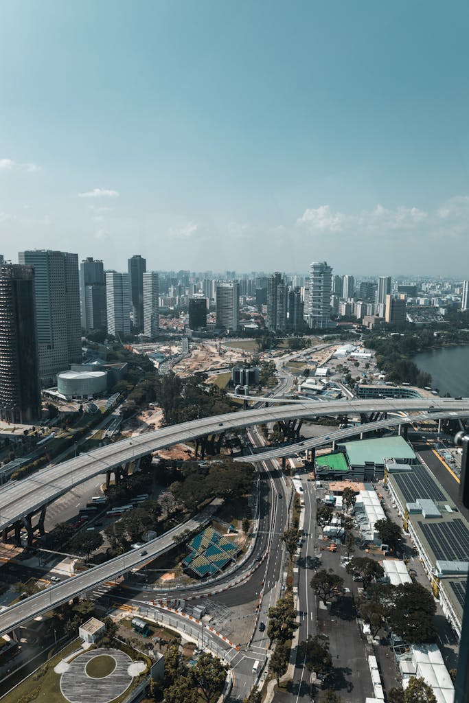 High vantage view of a city's modern skyline with elevated roads and skyscrapers under a clear blue sky.